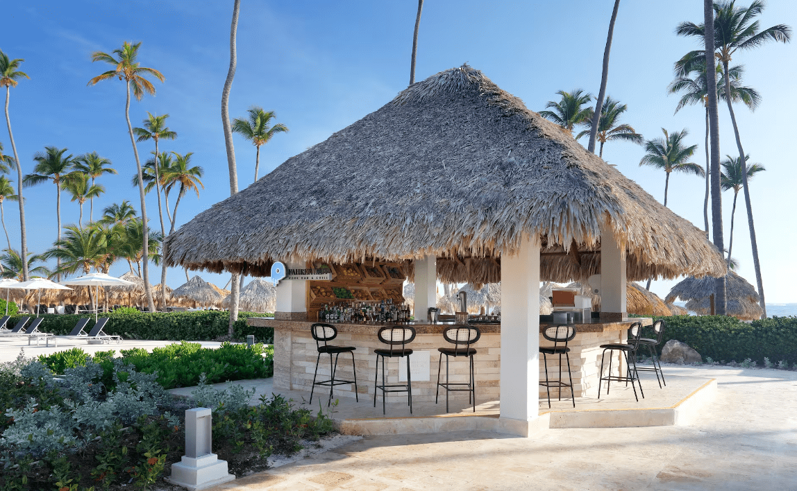 Beach bar with thatched roof and stools.