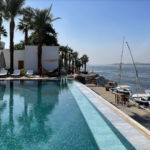 Swimming pool with view of river and boats.