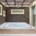 Stone wall spa with jacuzzi and flowers.