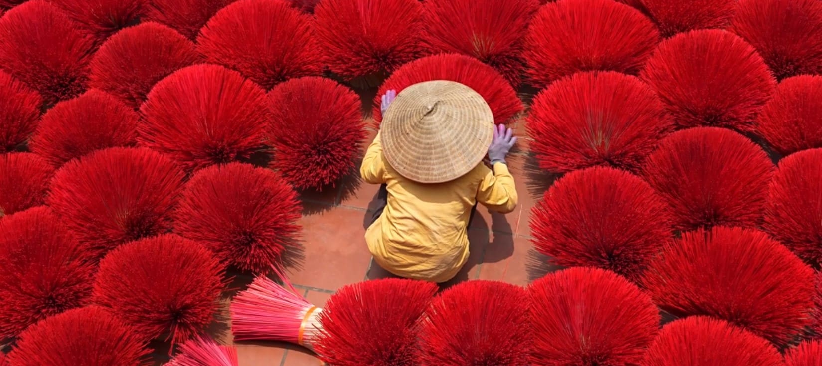 Person making red incense sticks.