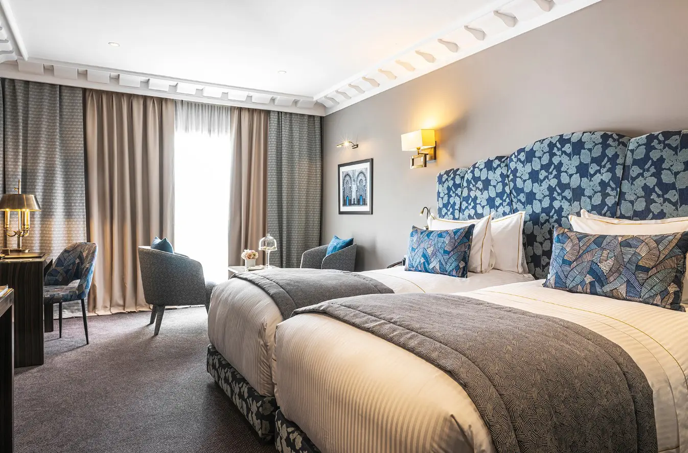 Hotel room with twin beds and curtains.