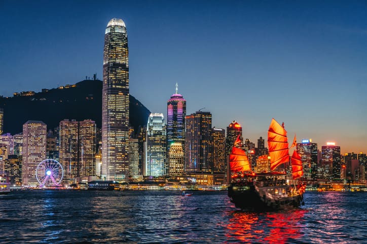 Night view of Hong Kong skyline with a junk boat.