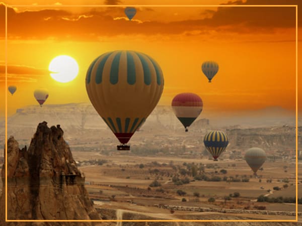 Hot air balloons floating over a sunset.