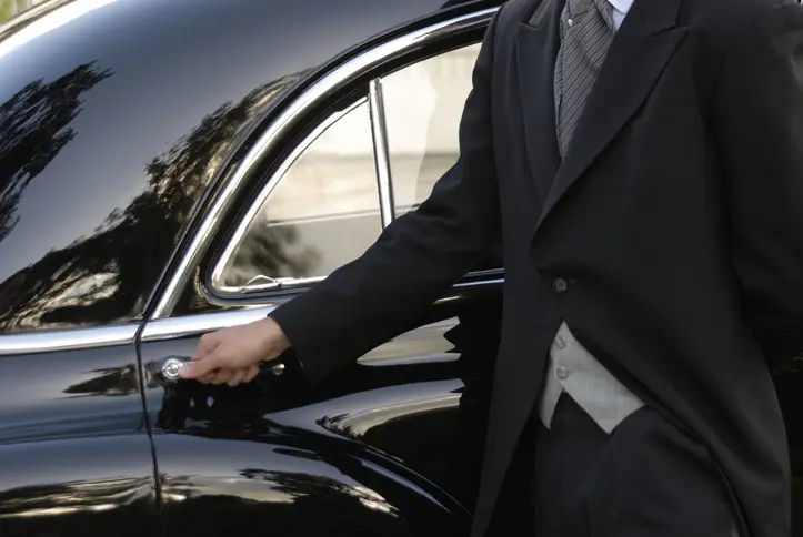 Man in suit opening a car door.