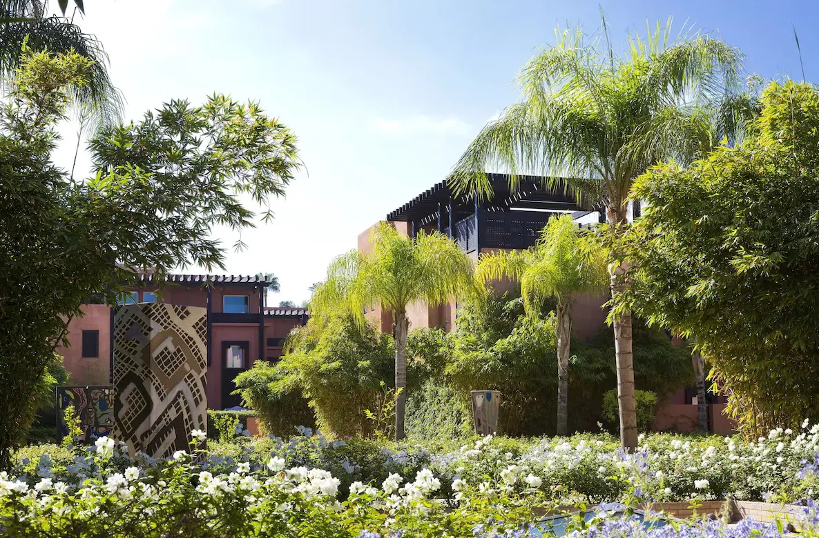 Palm trees and flowers by a building.