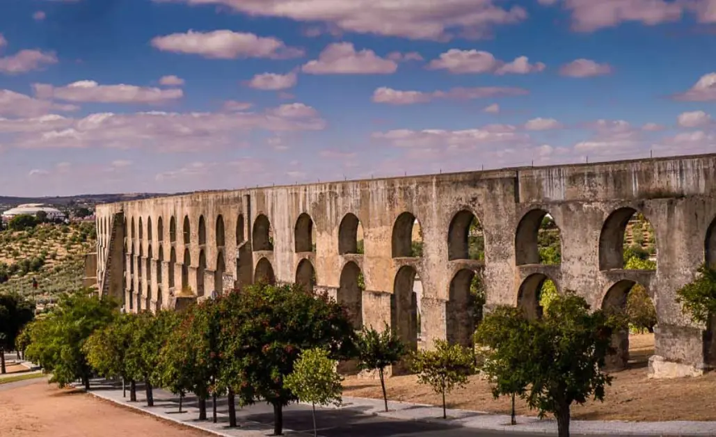 Stone aqueduct with trees and blue sky.