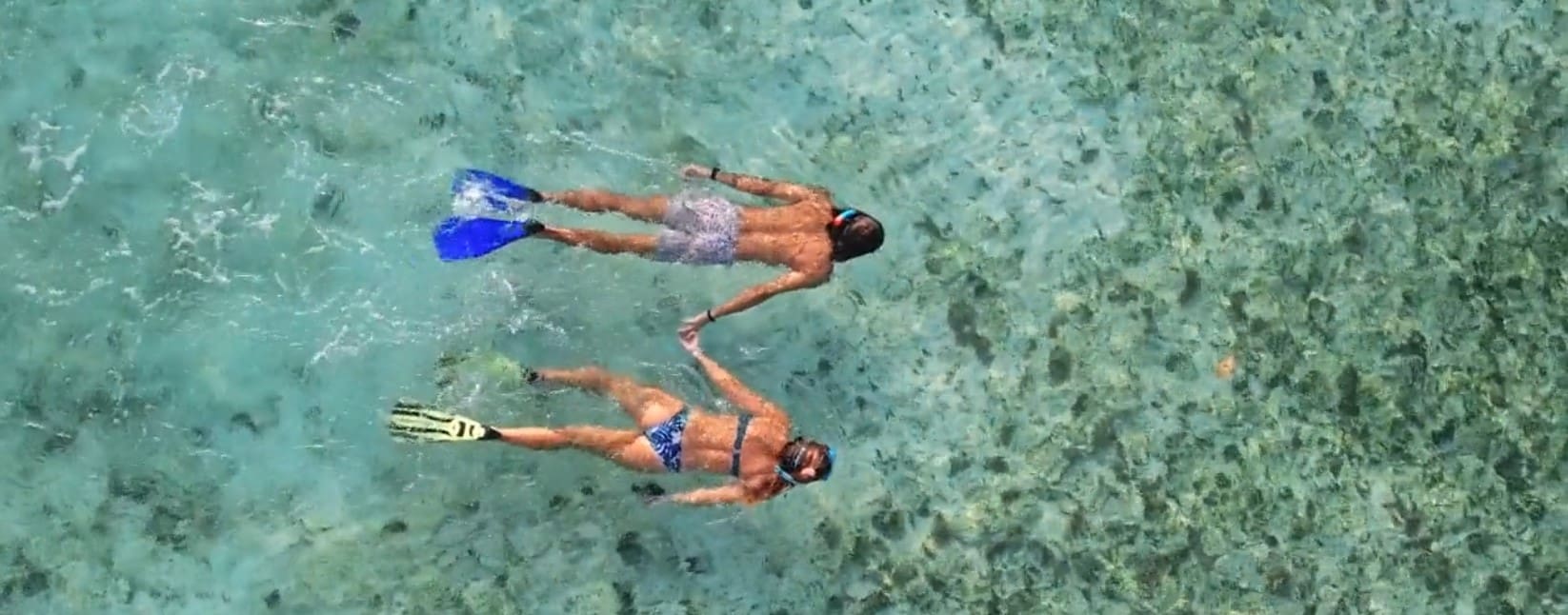 Couple snorkeling in clear blue water.