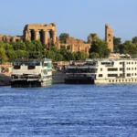 Two cruise ships docked near ancient temple.