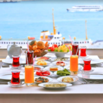 Breakfast table with tea and fruit, water view.