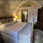 Stone room with a bed and ornate headboard.