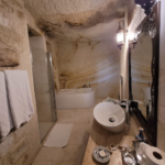 White bathroom with cave-like ceiling and sink.