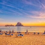 Beautiful beach with lounge chairs at sunset.