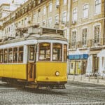 Yellow tram on cobblestone street.