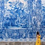 Woman in yellow dress near blue tile mural.