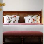 Cozy bedroom with decorative pillows and bench.