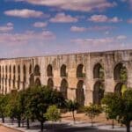 Ancient aqueduct with arches and trees.