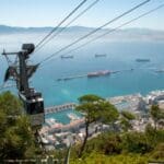 Cable car overlooking a coastal city and ships.