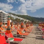 Beach lounge chairs with colorful umbrellas.