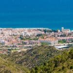 Coastal city view with mountains in foreground.