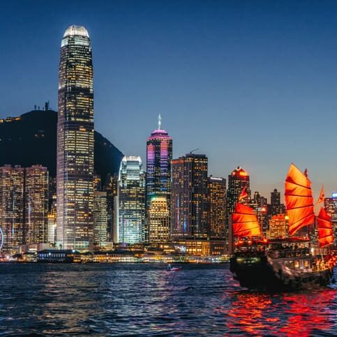 Night view of Hong Kong skyline with a junk boat.