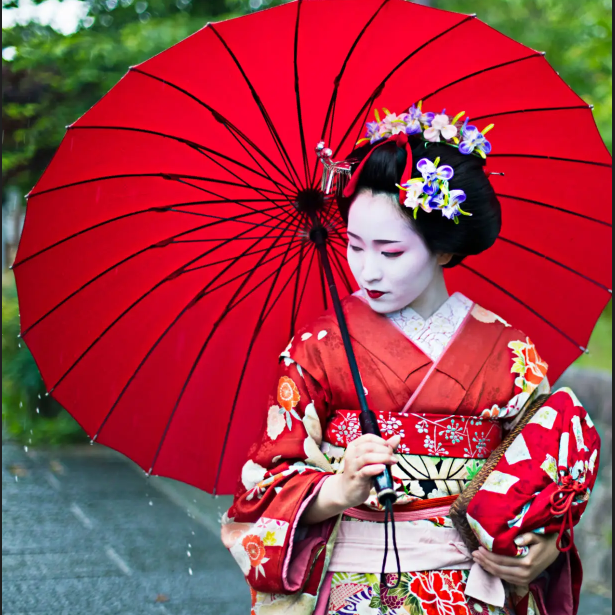 Woman in kimono holding red umbrella.